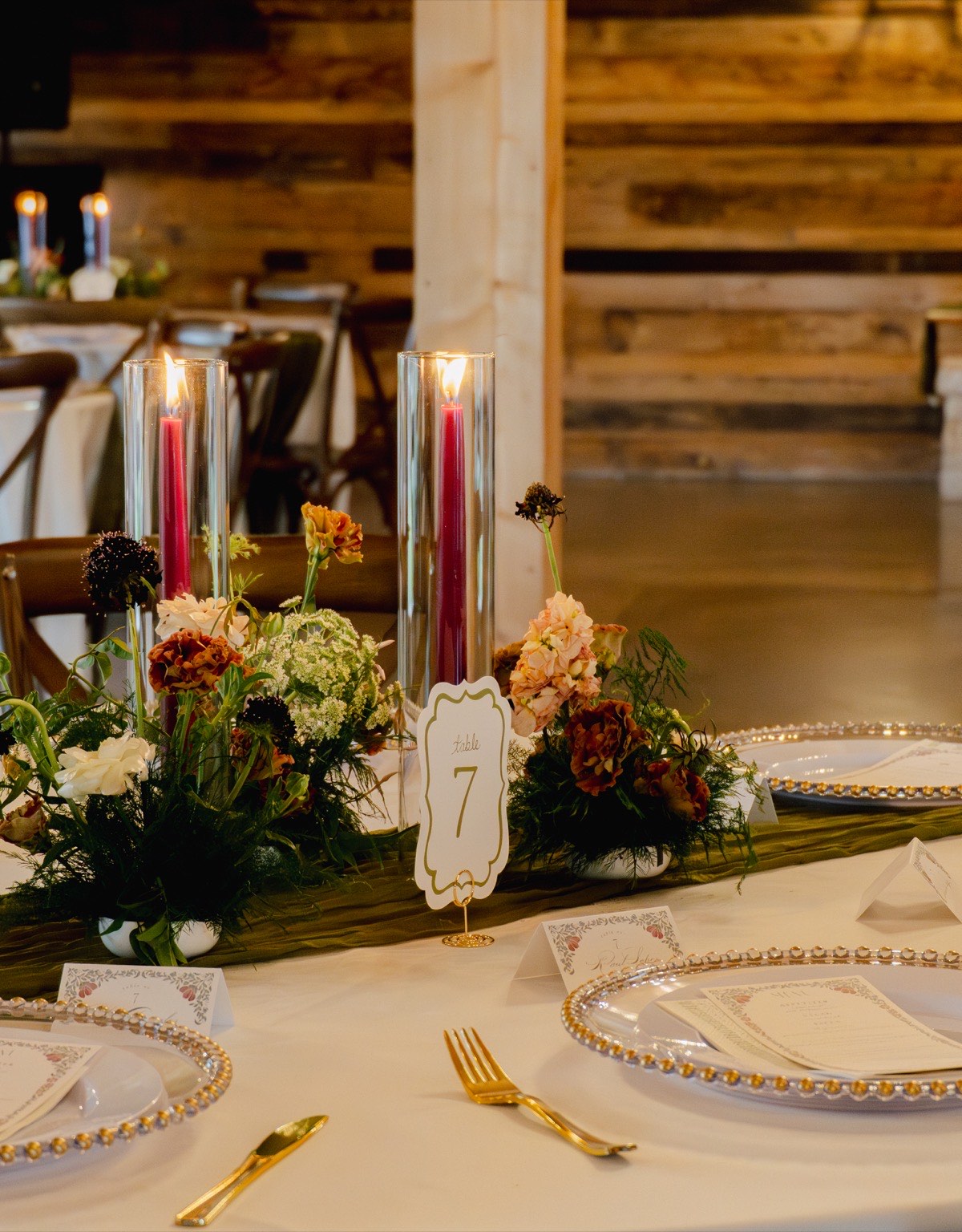 Reception table at The Melissa Barn with flowers, candles and gold-accented place settings