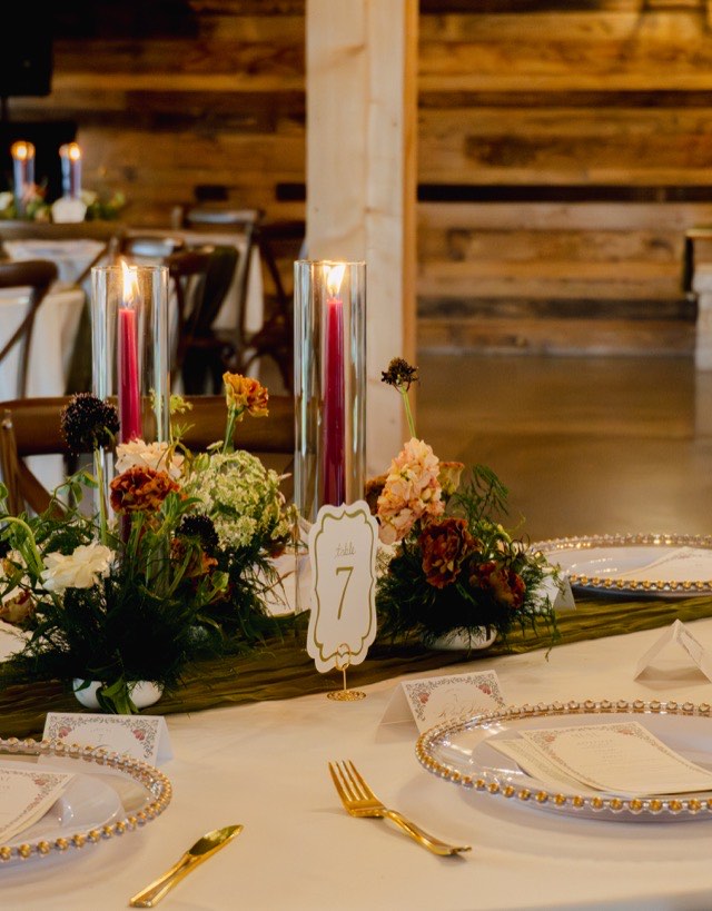 Styled reception table at The Melissa Barn with flowers, candles and gold-accented place settings