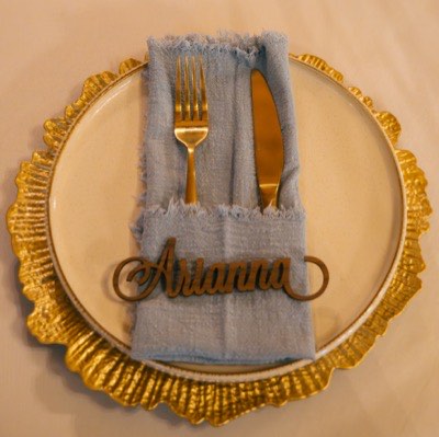 Styled gold charger place setting with a blue napkin and personalized detail